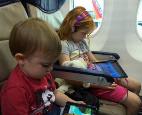 two small children on page watching ipads